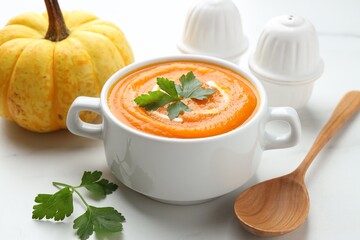 Tasty pumpkin cream soup served on white table, closeup