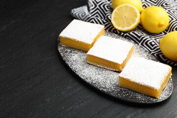 Tasty lemon bars and fresh fruits on black table, closeup. Space for text