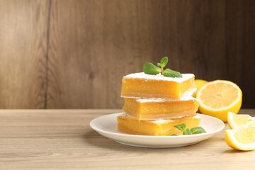 Tasty lemon bars with mint and fresh fruits on wooden table, closeup. Space for text