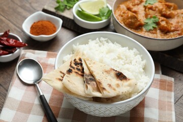 Delicious rice, lavash, chicken tikka masala and spices on wooden table, closeup