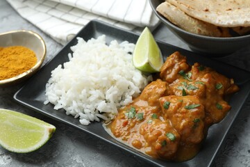 Chicken tikka masala with rice served on grey textured table, closeup