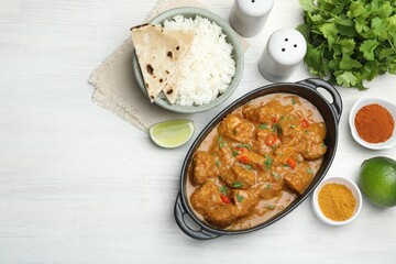 Chicken tikka masala, rice with paratha and spices on white wooden table, flat lay. Space for text