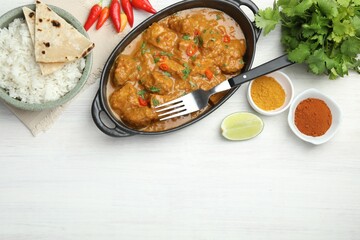 Chicken tikka masala, rice with paratha and spices on white wooden table, flat lay. Space for text