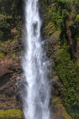 Giant waterfall cascading flow of water surrounded by lush scenery