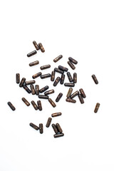 Scattered elongated dark brown beads on a clean white background surface