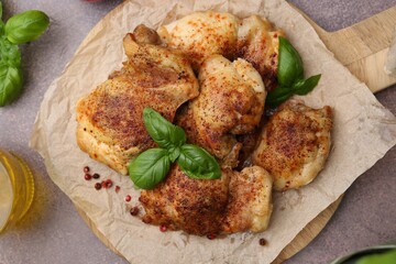 Tasty roasted chicken thighs with basil and oil on grey table, flat lay