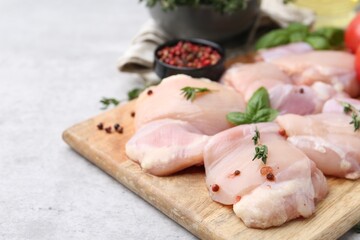 Raw chicken thighs with herbs and peppercorns on light table, closeup