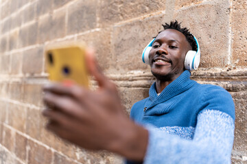 African man with headphones taking a selfie using smartphone during city vacation