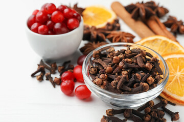 Different spices, cranberries and dry orange slices for mulled wine on white wooden table, closeup