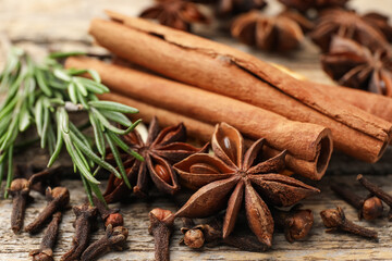 Different spices and fresh rosemary for mulled wine on wooden table, closeup