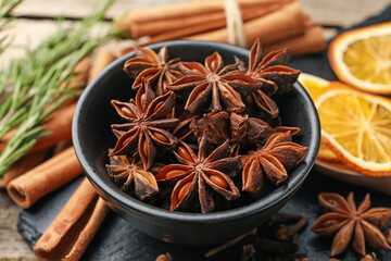 Mulled wine spices. Anise stars in bowl, cinnamon sticks, dry orange slices and fresh rosemary on table, closeup