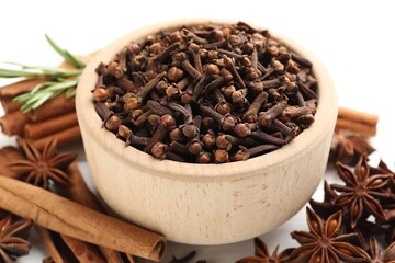 Mulled wine spices. Cloves in bowl, anise stars and cinnamon sticks on white table, closeup
