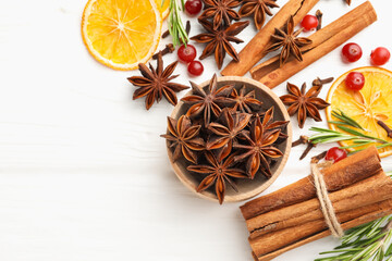 Different spices, dry orange slices, cranberries and fresh rosemary for mulled wine on white wooden table, flat lay. Space for text