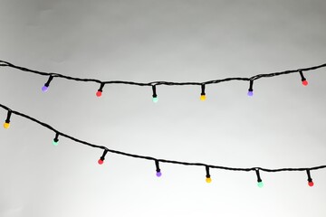 Bright Christmas lights on grey background, closeup