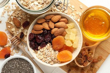 Making granola. Oat flakes, dried fruits and other ingredients on white table, flat lay