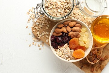 Making granola. Oat flakes, dried fruits and other ingredients on white table, flat lay. Space for text