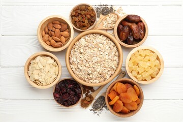 Making granola. Oat flakes, dried fruits and other ingredients on white wooden table, flat lay