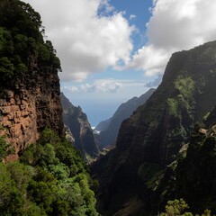 Dramatic Lush Green Canyon Overlooking Blue Ocean Under a Cloudy Sky on a Sunny Day