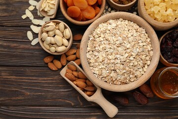 Making granola. Oat flakes, dried fruits and other ingredients on wooden table, flat lay