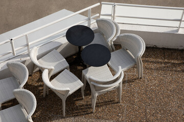 chairs and tables in a restaurant overhead view of white wicker chair and black table unoccupied...