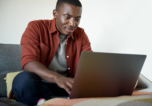 Young African man working remotely from home on a laptop - Powered by Adobe