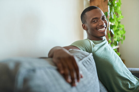 Smiling young African man relaxing on his sofa at home