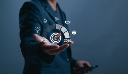 Businessman hand holding 2025 to 2026 goal progress bar with target icon. Concept of business planning, future strategy, performance improvement and digital transformation timeline