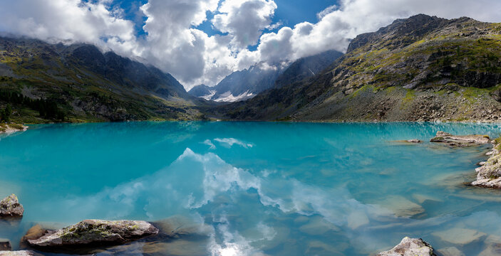 Majestic mountain lake with turquoise water and dramatic cloudscape in serene valley, banner