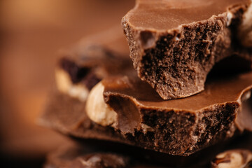 Close-up stacked chocolate pieces with crunchy texture and nuts on warm brown background for dessert branding and confectionery advertising