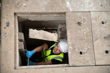 Environmental scientists climb ladders down to drainage channels around the city.