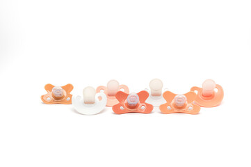 Different colored pacifiers in a row on a white background