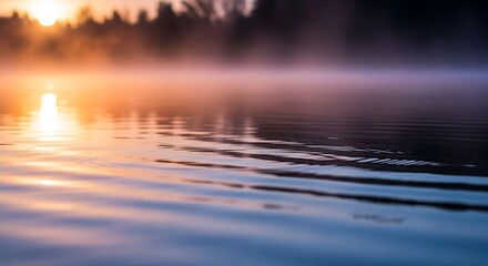 Golden hour sunrise over misty lake with gentle ripples on the water's surface