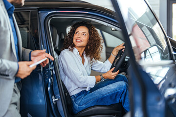 Confident Woman In Car With Salesperson During Vehicle Purchase Consultation At Dealership Showroom Today