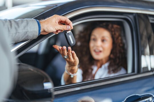 Happy Customer Receives Car Key Through Window During Purchase Exchange at Dealership