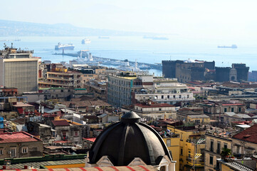 Aerial view of Naples, Italy. rooftops of residential houses and churches. dense cityscape. ships and sea port at far. travel and tourism. panoramic view from the hill above the city. colorful skyline
