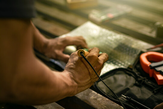 Close-up of a man using a soldering iron on an electronic circuit board on a table