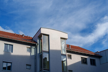 Modern building against a clear blue sky with scattered clouds in the late afternoon