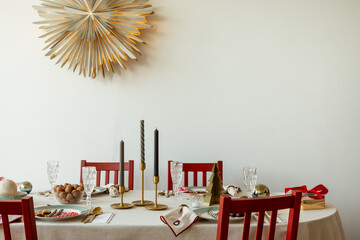 Fototapeta premium Elegant Christmas table setting with gold candle holders, crystal glasses, festive plates, and subtle holiday details.