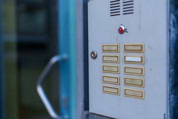 Control panel for apartment intercom system located at the entrance of a residential building during evening hours