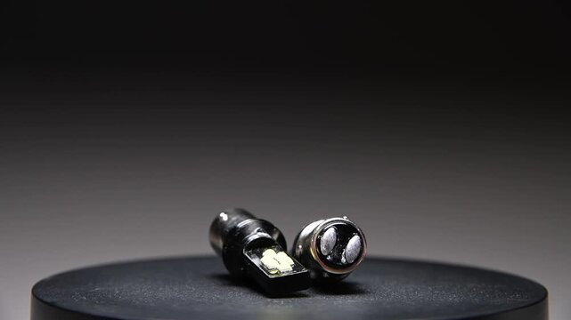 LED bulbs with different bases rotate on a gray gradient background. New parts for car interior and exterior lighting.