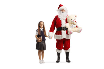 Full length portrait of Santa Claus holding hands with a girl and carrying a teddy bear