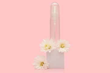 Transparent container with white flowers on a white podium on a pink background.