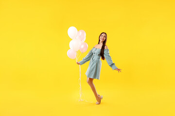Beautiful woman with balloons on orange background