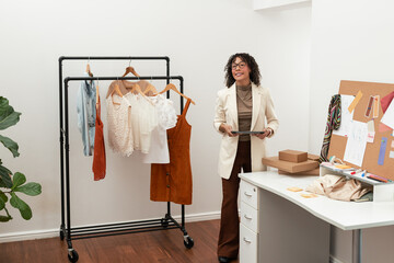 African American woman designer holding tablet, reviewing sketches in studio, copy space