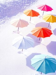 A collection of vibrant, open umbrellas are arranged on a textured white surface, creating a visually striking pattern with their colorful canopies and shadows.