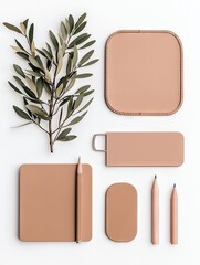 A collection of minimalist stationery items and an olive branch are arranged on a white surface.