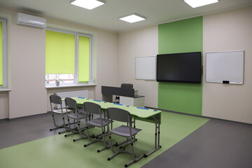 Classroom with green desks, chairs and tv at school