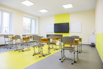 Stylish classroom with desks, chairs and tv at school