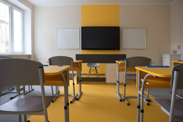 Stylish classroom with desks, chairs and tv at school