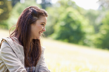 Naklejka premium Female smiling in profile standing left in sunlit meadow wearing light beige jacket and hair clip